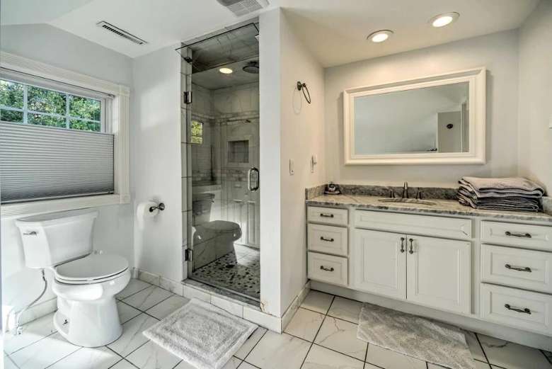 large bathroom with a sink and counter, a mirror on the wall, a toilet, and a shower