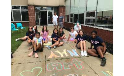 group of girls outside school sitting on the sidewalk with chalk drawings