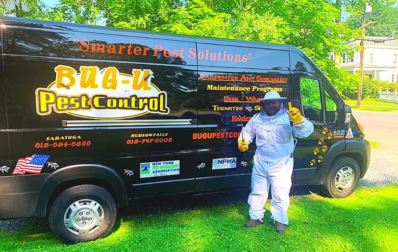 man in a pest control suit standing outside a black van