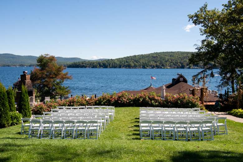 chairs set up on a grassy lawn for a wedding ceremony with a lake in the background