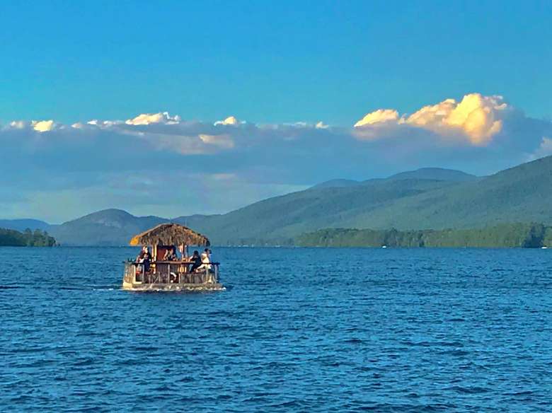 view of a tiki boat on a lake with mountains in the back