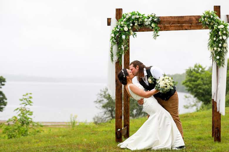 bride and groom kissing under a ceremony arch outdoors
