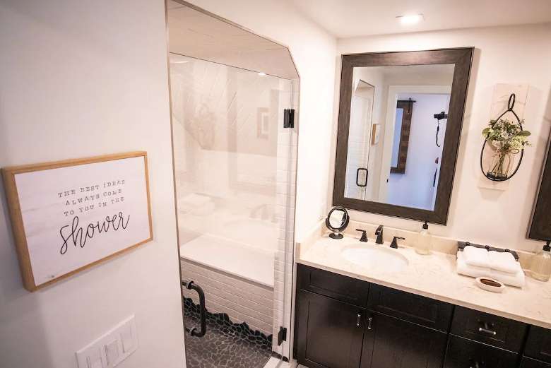 bathroom with sink, mirrors, and separate room with glass tub