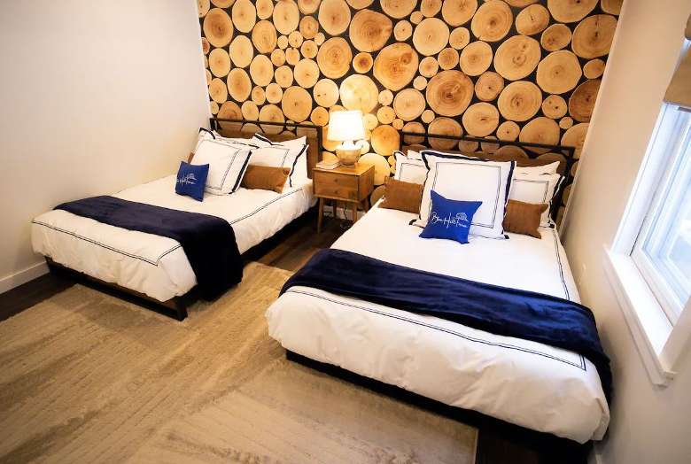 two beds side by side with log themed wall behind