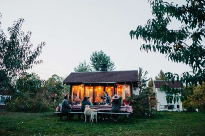 people seated at an outdoor table with a cabin nearby