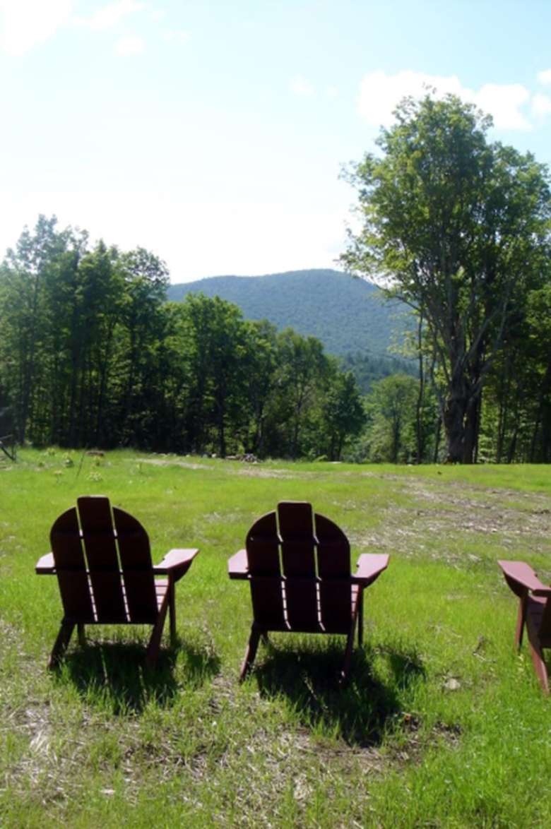 two adirondack chairs facing a view of mountains and trees