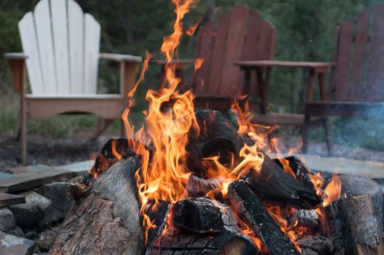 three chairs around a fire pit with burning wood