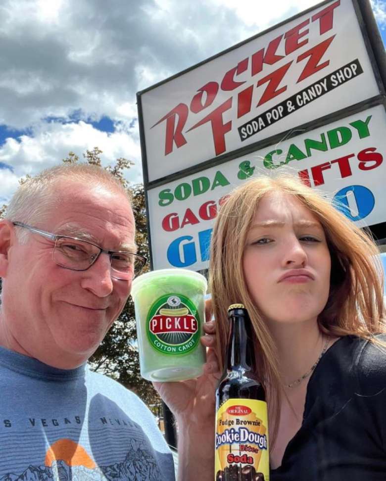 man and woman holding up pickle cotton candy and soda pop