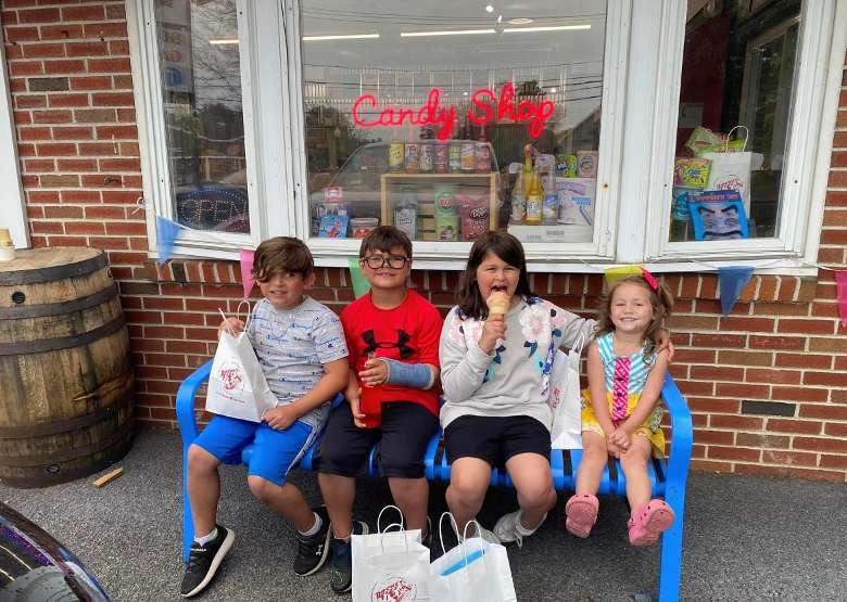 four kids on a blue bench outside a candy shop