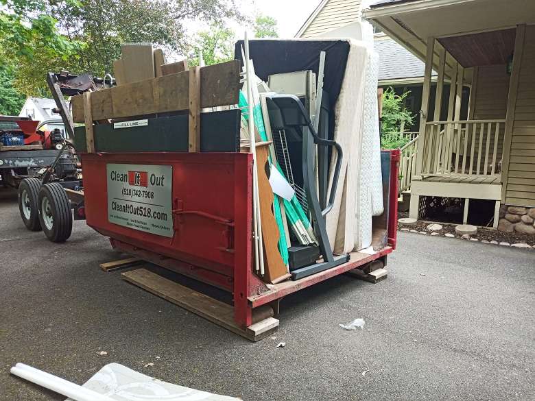 red dumpster filled with house junk