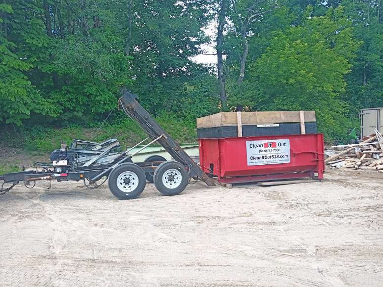 red dumpster being unloaded from a trailer