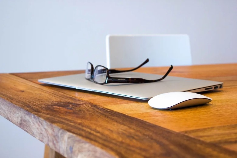 closed laptop, computer mouse, and glasses