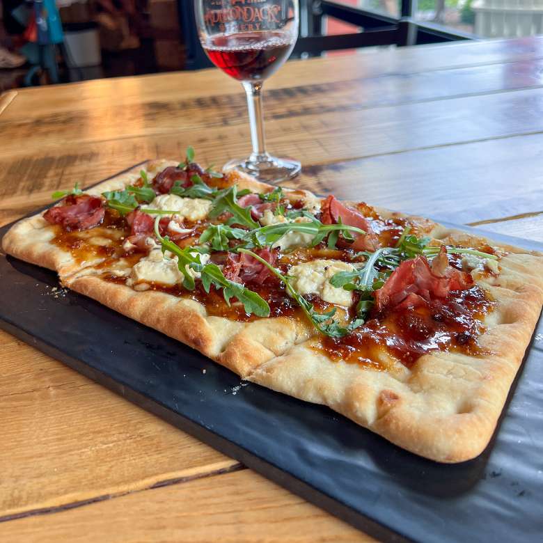 flatbread pizza with glass of wine behind it