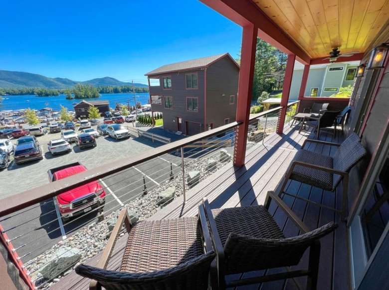 a deck on a house overlooking a parking lot and a lake