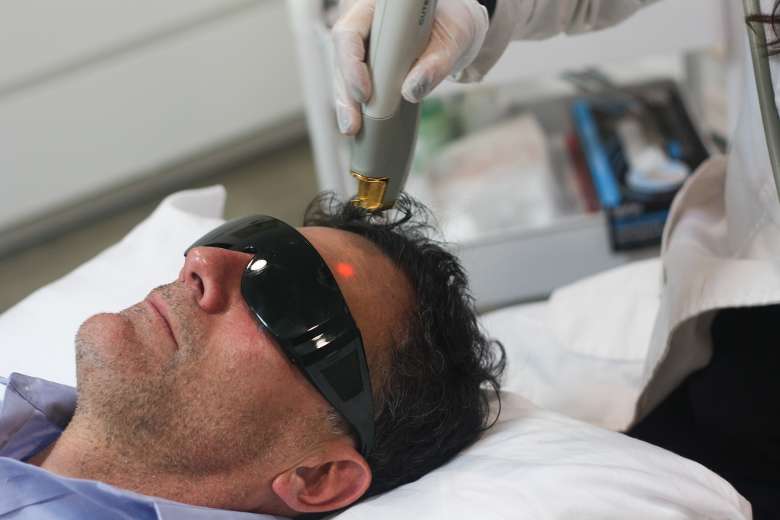 man with dark glasses on receiving a laser facial treatment