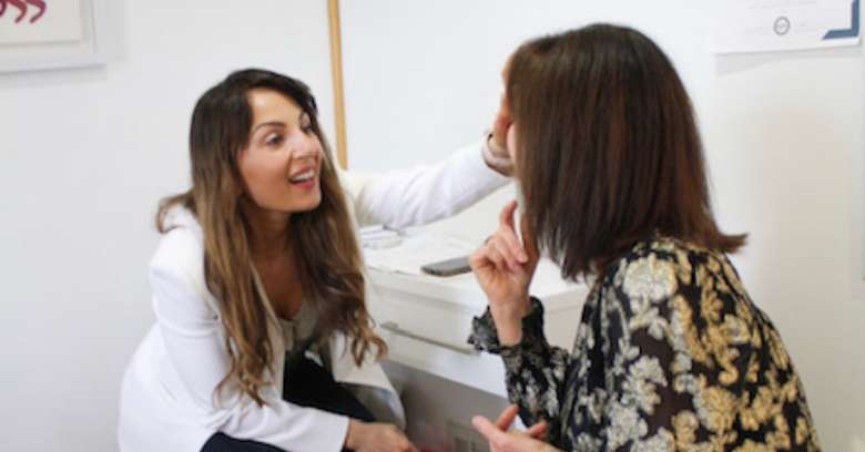 female medical laser technician examining woman's face