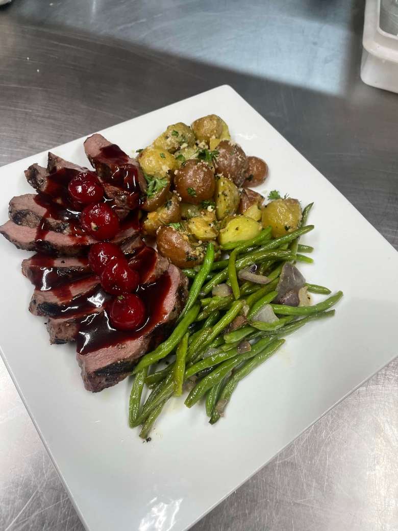 a plate with meat, green beans, and potatoes