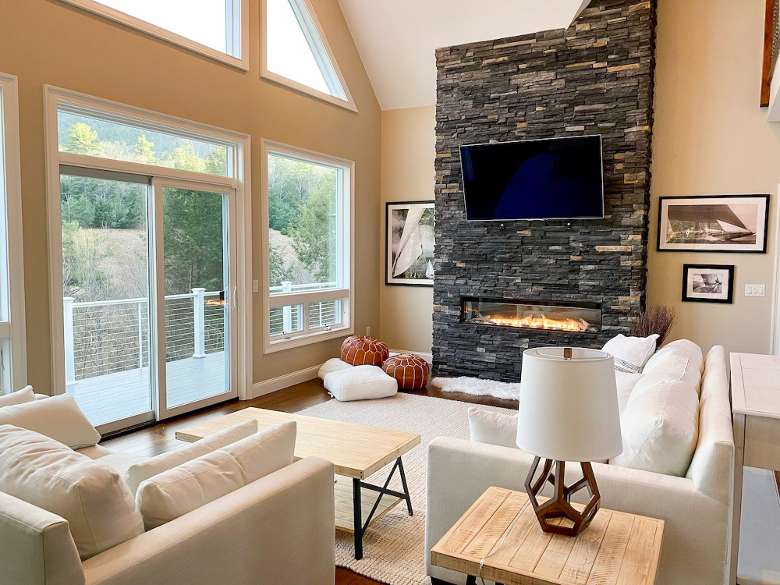 a living room area with white couches and a stone fireplace