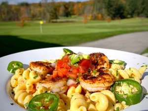 plate of macaroni and shrimp with view of golf course in the background
