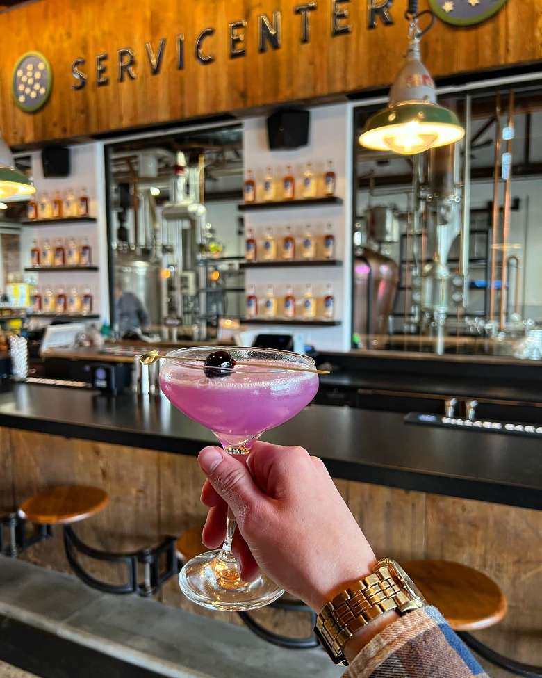 a person holding up a pink cocktail