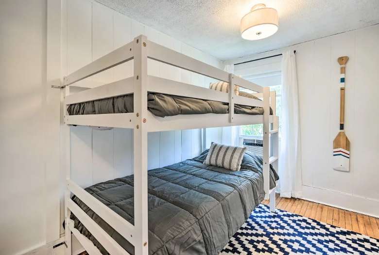 bedroom with a bunk bed, a paddle on the wall, a blue and white rug, and ceiling light