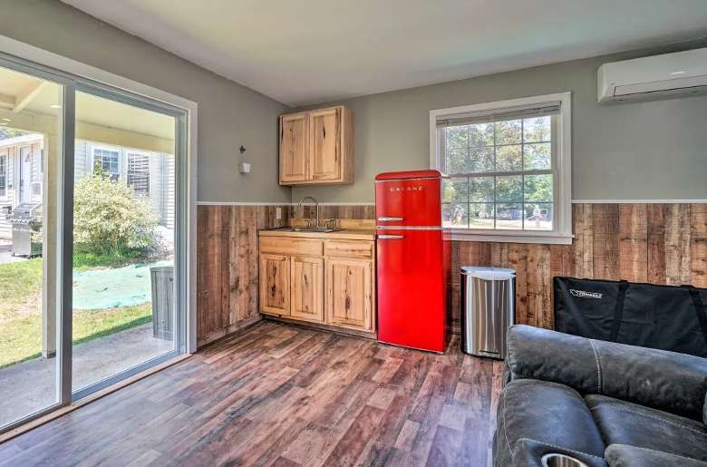 a room in a house with a red fridge, a sink, and a sliding glass door leading to a backyard patio