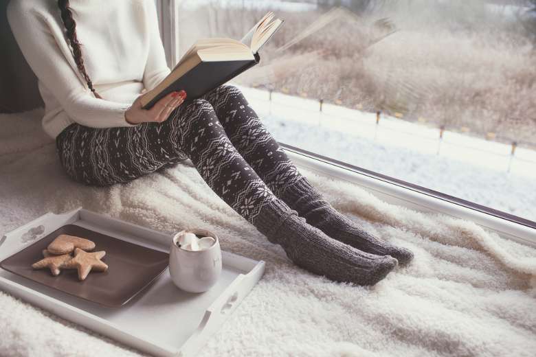 cozy looking woman reads book by window