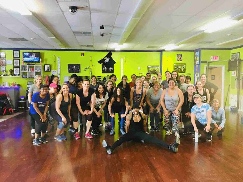 large group of people in a fitness room posing for a photo