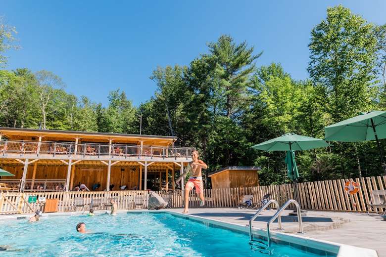 kid jumping into a pool outside of a lodge