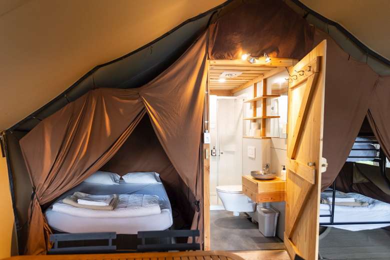 inside of a glamping tent with sleeping areas, and a bathroom in the back