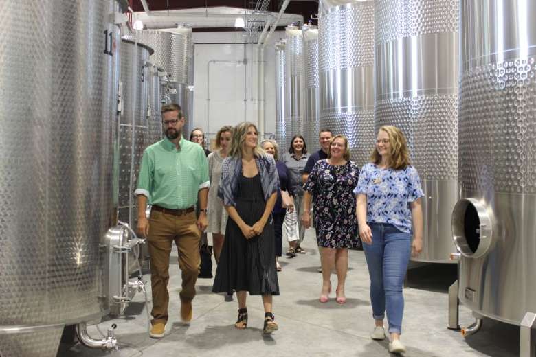group of people walking by winery tanks