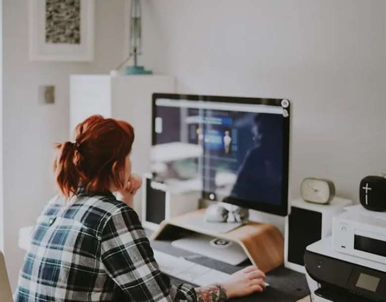 woman in a plaid shirt at a desktop computer