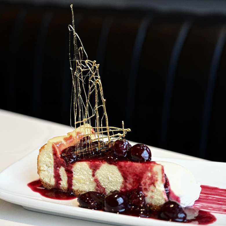 slice of cheesecake with cherries and a syrupy design on top