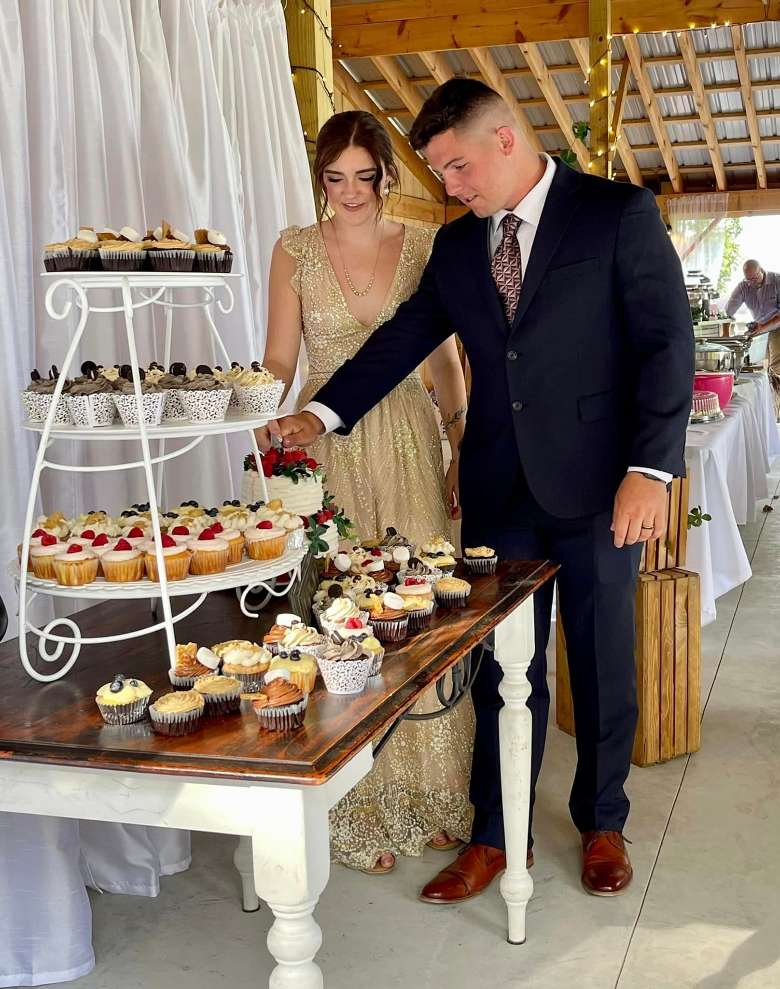 bride and groom cutting the wedding cake by a dessert table