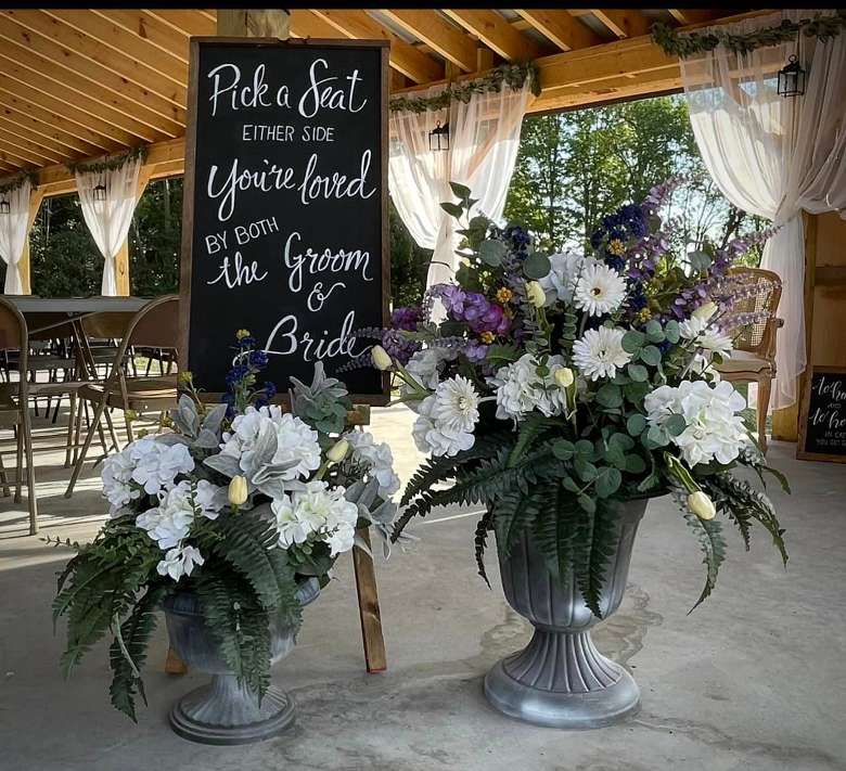 a greeting sign by flower stands in a rustic wedding venue