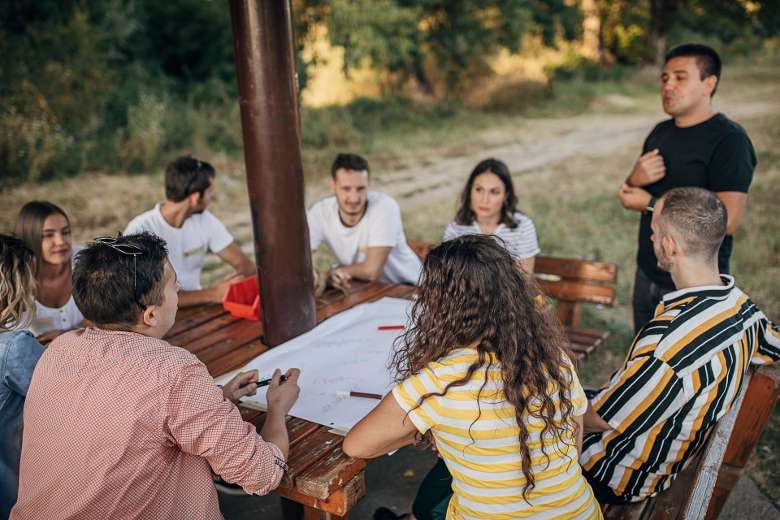 people seated around an outdoor table with a planning sheet on it