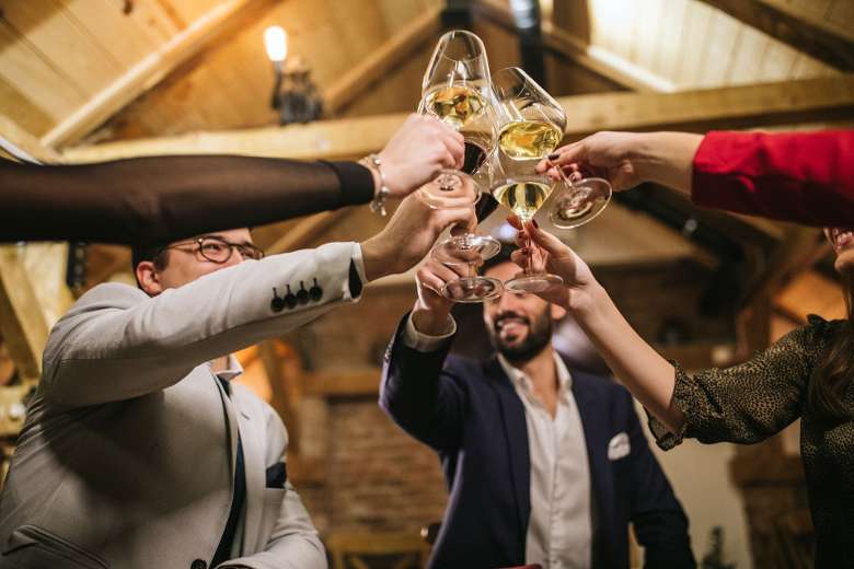 a group of people holding up wine glasses in a rustic barn space