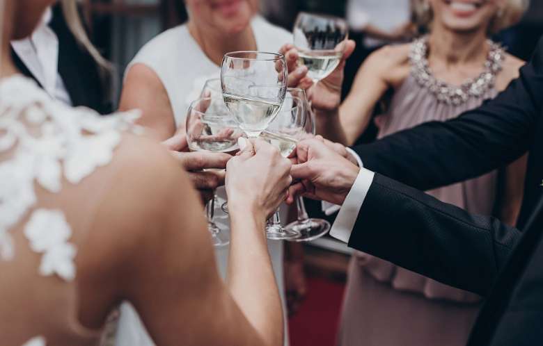 people dressed for a wedding raising wine glasses together in celebration