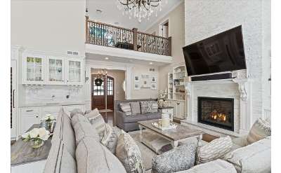 a large living room with couches, a table, a fireplace, and a big tv on the wall