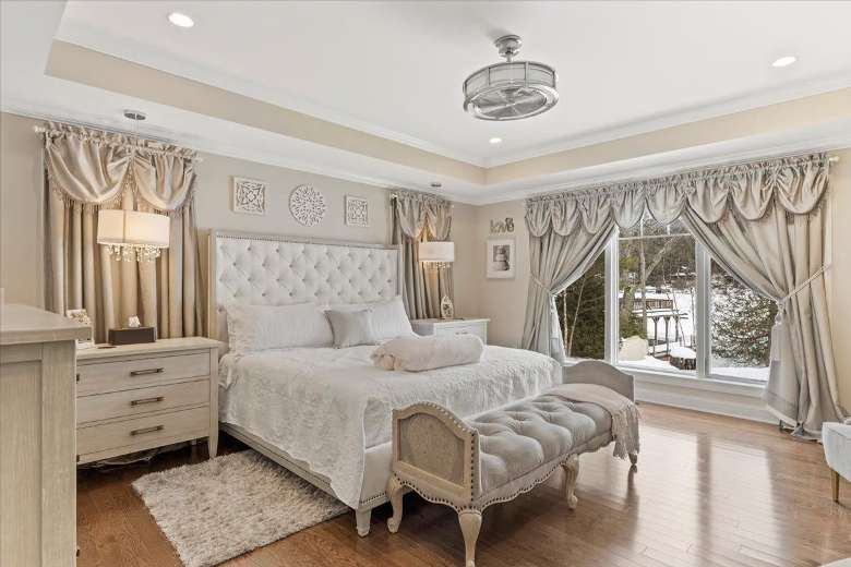 large bedroom in a house with a bed, bench, dresser, and sliding glass door