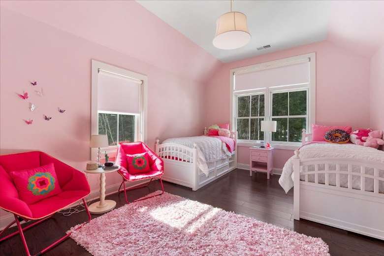 bedroom with two windows, pink walls, two red chairs, and two beds
