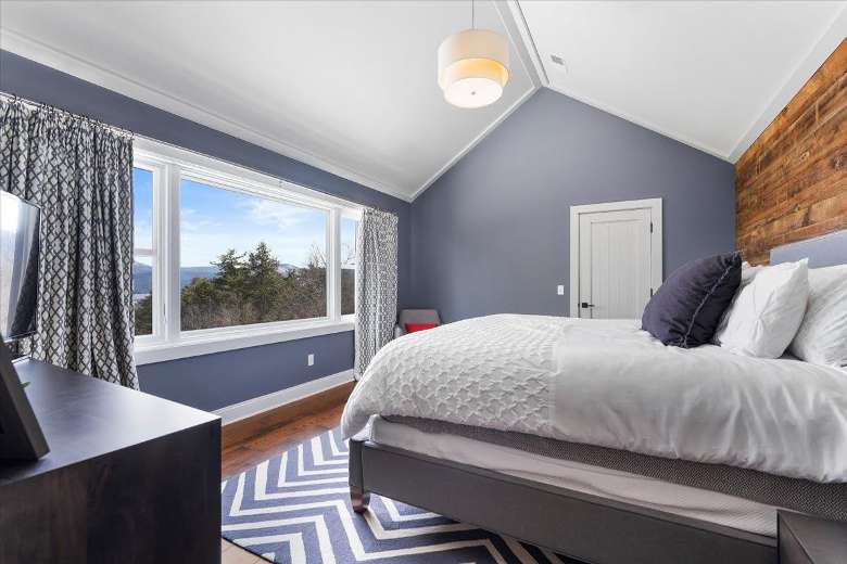 bedroom with gray walls, a bed with pillows, and a large window