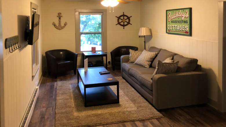 living room with nautical decor on the wall, a couch, chairs, and a table