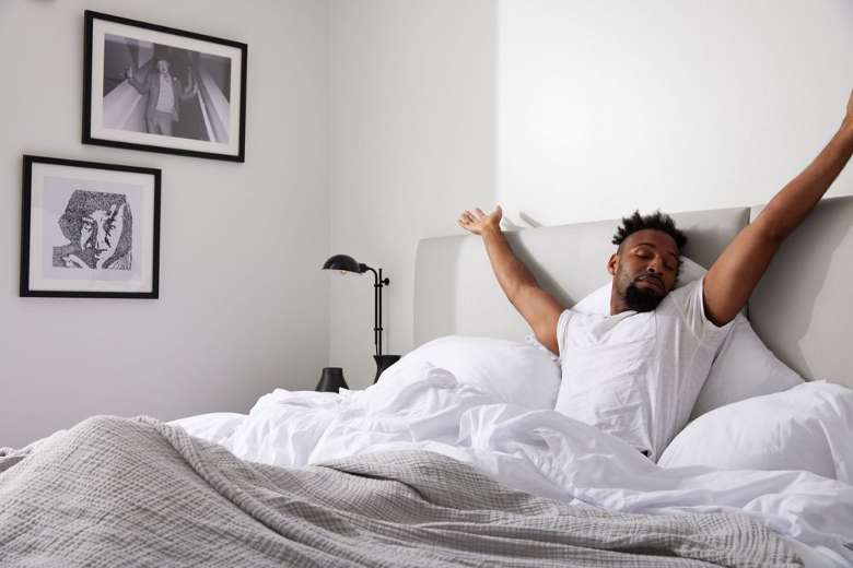 man waking up in a hotel room bed