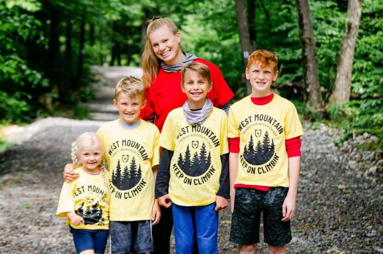 female summer camp counselor, three boys, and one girl