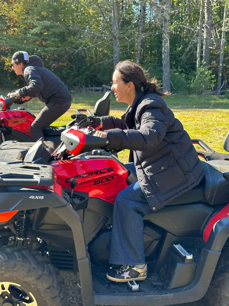 side view of two people riding on red ATVs
