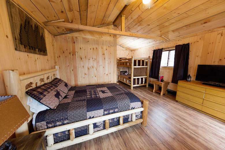 inside of cabin with wood walls, floors, ceilings, and a bed
