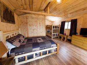 Inside of cabin with wood walls, floors, ceilings, and a bed
