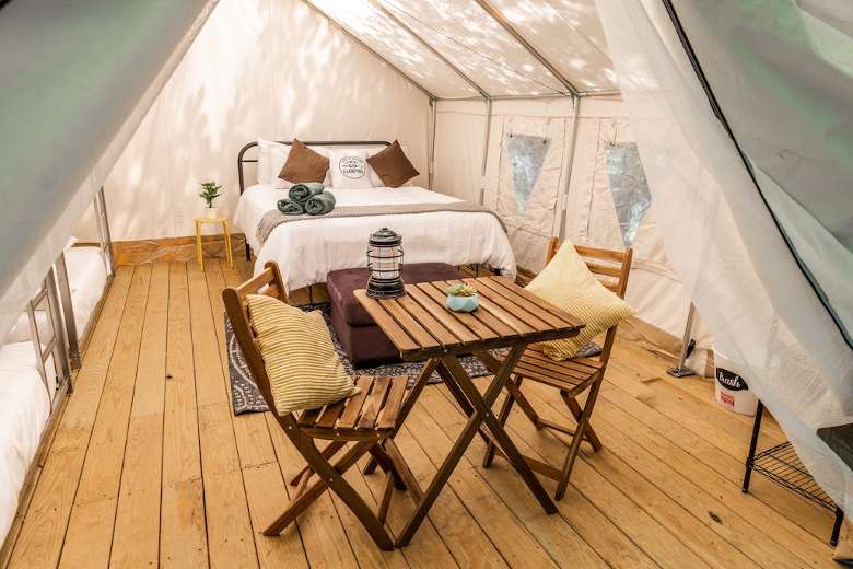 inside of a glamping tent with a table, chairs, and a bed