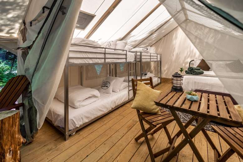 inside of a large glamping tent with bunk beds and a regular bed
